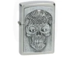 Briquet Zippo argenté brossé avec plaque en relief d'un crâne richement décoré de motifs ornementaux.
