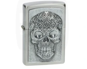 Briquet Zippo argenté brossé avec plaque en relief d'un crâne richement décoré de motifs ornementaux.